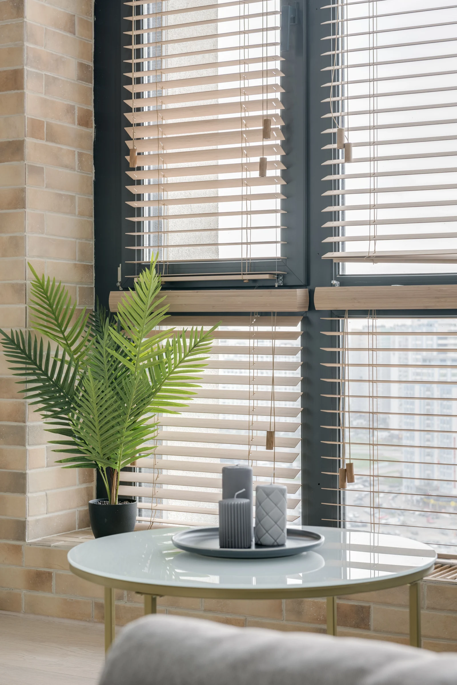 Venetian blinds filtering light beside a plant and side table